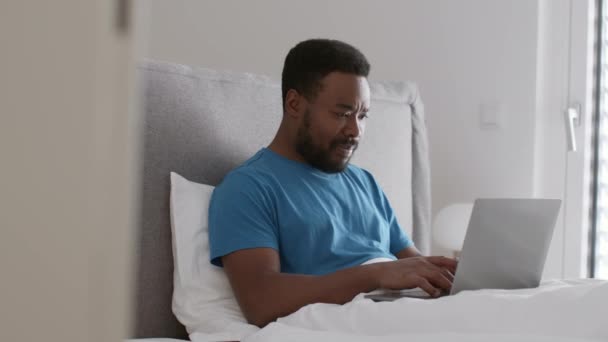 Молодий Афроамериканський Чоловік Працюєголовним Чином Ноутбуці Ліжку Працює Вдома Вихідні — стокове відео