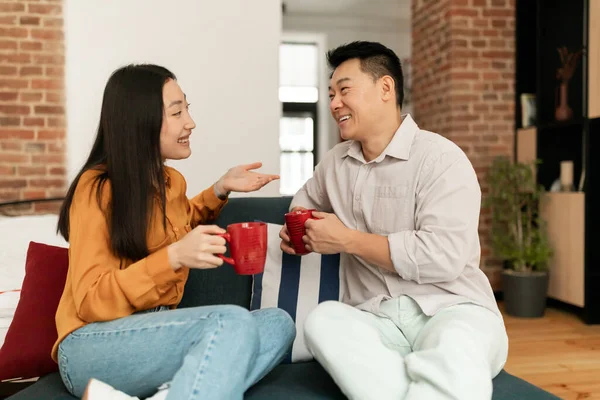 Happy Asian Spouses Sitting Sofa Cups Hot Drink Talking Resting — Photo