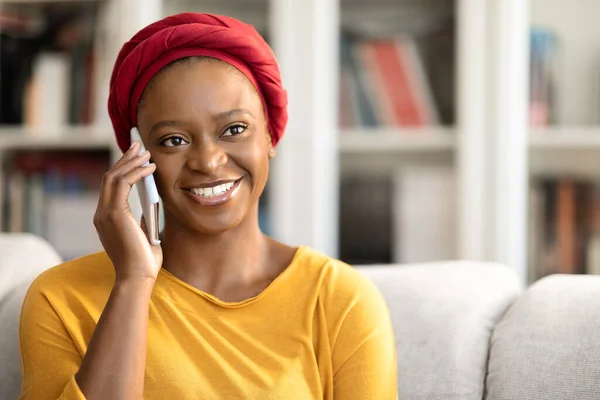 家で凍えている間に電話で会話をしながら コピースペースを見て 笑顔で クローズアップしている赤いスカーフを着た陽気な幸せな魅力的な若い黒人女性 コミュニケーションの概念 — ストック写真