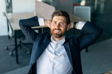 Taking break. Relaxed happy caucasian businesswoman resting on chair, leaning back at workplace in office and smiling at camera. Happy man holding hands behind head