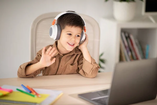 Cheerful Little Boy Wireless Headphones Sits Table Studies Has Video — Stock Photo, Image