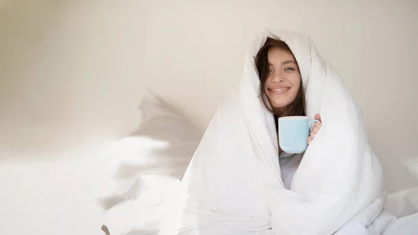 Cheerful Young European Woman Wrapped White Blanket Sits White Bed — Stok fotoğraf