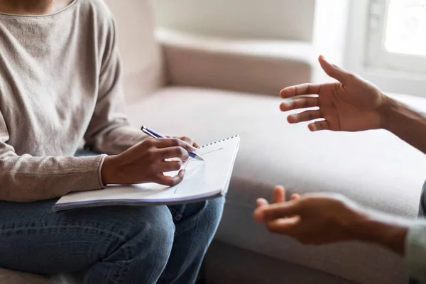 stock image Cropped of black woman therapist holding folder and pen, african man gesturing while have professional aid psychological help, hands of unrecognizable doctor and patient, close up, copy space