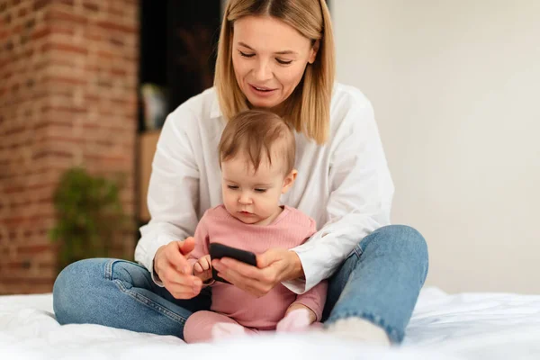 Happy Mom Her Little Daughter Using Smartphone Sitting Bed Home — Fotografia de Stock