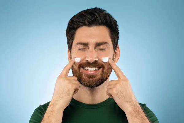 Happy Bearded Handsome Man Applying Face Cream Cheeks Closed Eyes — Foto de Stock
