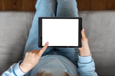Unrecognizable Woman Using Blank Digital Tablet With White Screen At Home, Top View Shot Of Young Female Relaxing On Couch With Modern Gadget, Browsing New App Or Website, Mockup With Copy Space