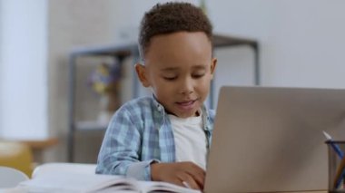 Kids and technologies. Close up portrait of little black boy pushing buttons on laptop keyboard, his daddy coming and fixing mistakes, free space