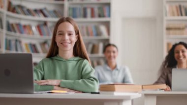 Positive offline education. Portrait of young pretty ladies students smiling to camera at classroom, sitting at desks during lessons, selective focus, slow motion, free space