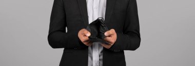 Bankruptcy Concept. Business Person Holding Empty Wallet In Hands, Unrecognizable Businessman In Suit Having No Money, Standing Isolated Over Grey Background, Cropped Shot, Panorama