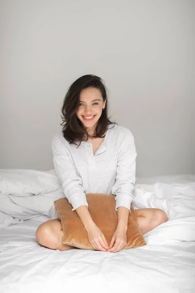 Cheerful Young European Woman Sitting White Comfortable Bed Hold Pillow — Stok fotoğraf