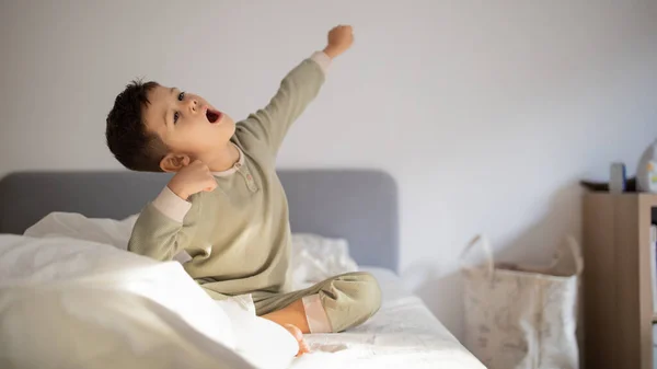 Cheerful Active Caucasian Little Child Wake Sits Bed Stretching Body — стоковое фото