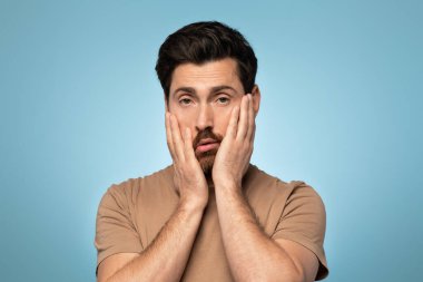 Handsome caucasian man looking sleepy and tired, exhausted for fatigue and hangover, lazy eyes in the morning, male standing over blue background