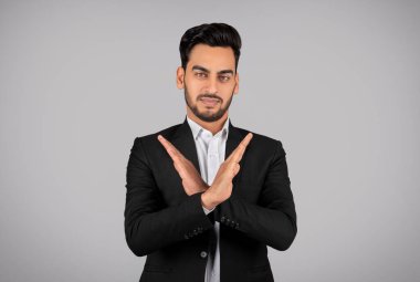Refusal Concept. Young Arab Businessman Showing Stop Gesture With Crossed Arms, Middle Eastern Male Entrepreneur Refusing Business Offer While Standing Isolated On Grey Background, Copy Space