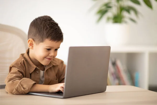 Cheerful Small European Boy Sitting Table Typing Computer Play Game — Φωτογραφία Αρχείου