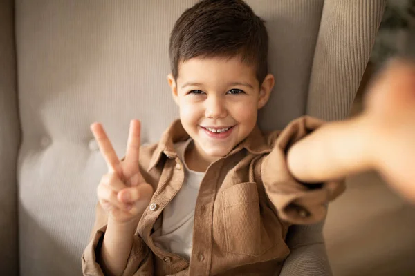 Smiling Cute Small European Boy Sitting Armchair Makes Selfie Peace — Stock Photo, Image