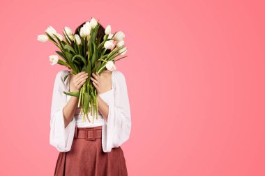 Young caucasian woman in casual covering face with bouquet of flowers, enjoy free time isolated on pink background, studio. Sale at spring, celebration holiday, fashion and lifestyle, ad and offer