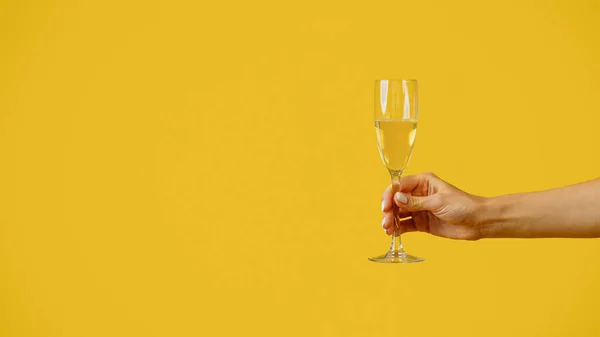 Female Hand Holding Glass Champagne Yellow Studio Background Panorama Free — Stockfoto