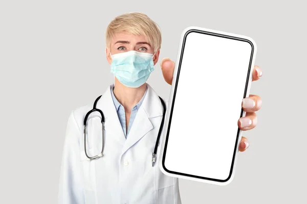 Female Doctor White Coat Protective Mask Showing Blank Smartphone Middle — Stock fotografie