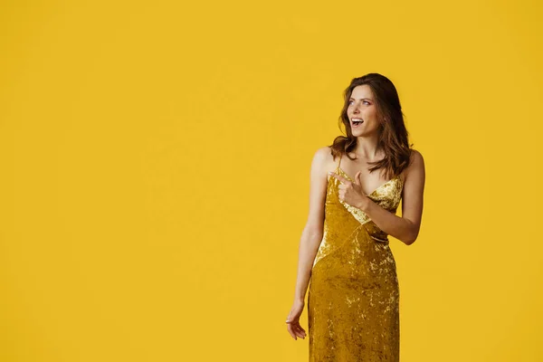 Seasonal sale. Excited lady in dress pointing at free space over yellow studio background, banner design. Surprised woman having special offer, advertising your product
