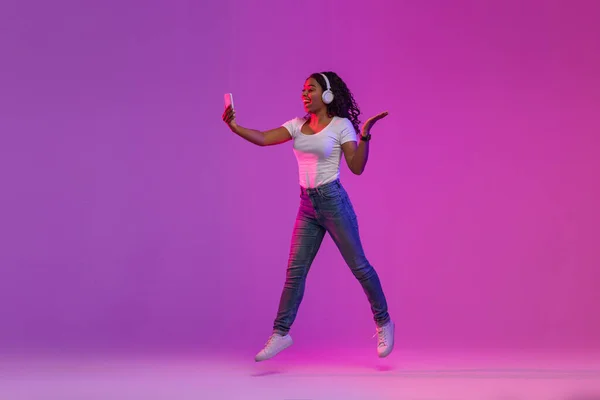 Joyful Black Woman Neon Light Jumping Smartphone Hands Cheerful African — Foto de Stock