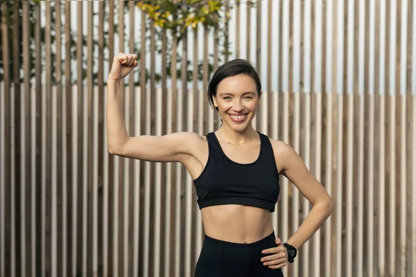 Cheerful Caucasian Millennial Muscular Slim Female Sportswear Shows Biceps Show — Stok fotoğraf