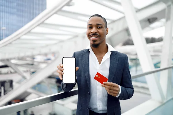 Usmívající Černý Podnikatel Ukazuje Smartphone Prázdnou Obrazovkou Kreditní Kartou Zatímco — Stock fotografie