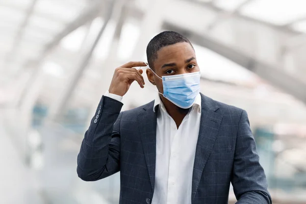 Young Black Businessman Taking Medical Face Mask While Walking Airport — Fotografia de Stock