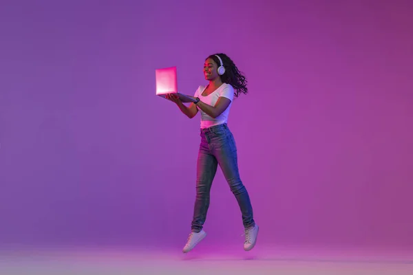 Positive African American Female Jumping Laptop Neon Lighting Cheerful Black — Foto de Stock