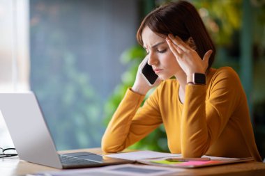 Distressed young businesswoman have phone call, upset lady sit at table alone, working at cafe, entrepreneur experiencing difficulties with business while crisis, needs for advice, copy space