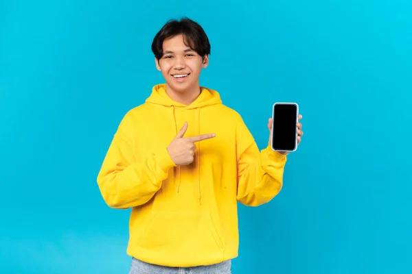 Cheerful Korean Teen Guy Holding Phone Empty Screen Pointing Finger — 스톡 사진