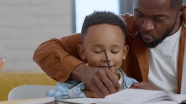 Preparing for school. Cute little boy study to write with daddy, exercising together at home and laughing, close up portrait, empty space