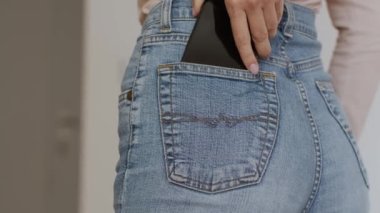 Tanımlanamayan kadınların yakın plan çekimleri cep telefonunu modaya uygun kot pantolonun cebine koy, arka görüş, yavaş çekim, boş alan