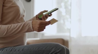 Online shopping. Profile shot of unrecognizable pregnant woman making financial transaction on smartphone, using credit card and mobile app, slow motion, free space