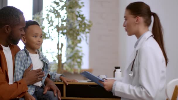 Barnavård Underbar Afrikansk Amerikansk Pojke Sitter Läkarmottagningen Med Pappa Kvinnlig — Stockvideo