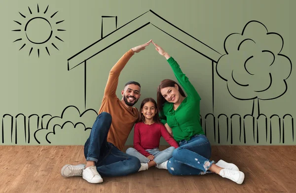 Cheerful mixed race family enjoying their new apartment, happy mother and father making roof above their daughter head, house sketch background, collage for moving, relocation concept