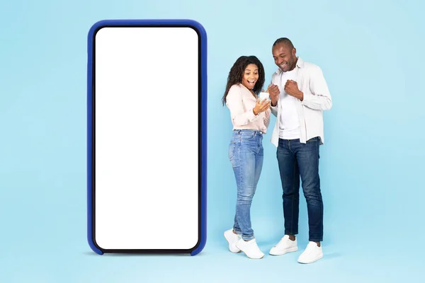 Excited Black Spouses Standing Big Smartphone Empty White Screen Using — Stock Fotó