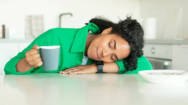 Tired Black Woman Sleeping Holding Coffee Cup Having Breakfast Early In The Morning Sitting At Table In Kitchen At Home, Being Late For Work. Exhaustion Concept. Panorama
