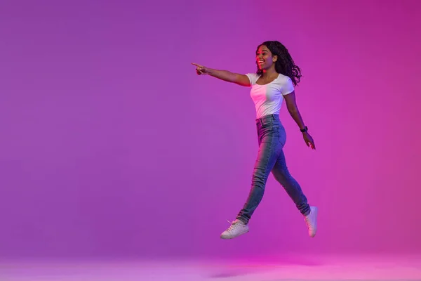 Look Happy Young Black Woman Jumping Neon Light Pointing Aside — Foto de Stock