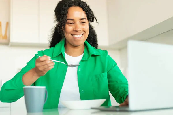 Alegre Mujer Afroamericana Usando Ordenador Portátil Desayunando Navegando Por Internet —  Fotos de Stock