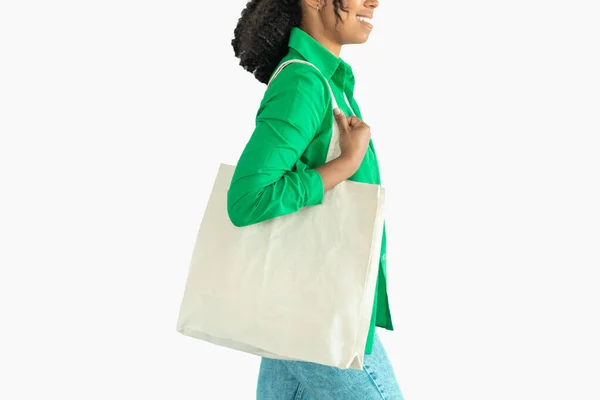 スタジオで白い背景に位置する認識できない黒の女性は テキスタイルショッパーバッグを運ぶ 現代のお客様の女性の撮影をトリミング プラスチック製ではない サイドビュー — ストック写真
