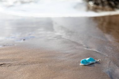 Disposable medical face masks and plastic pollution in nature, used personal protective masks and other coronavirus waste is polluting ocean, free space