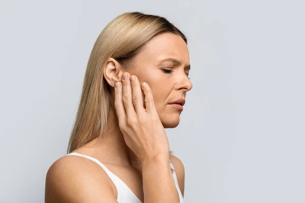 Tinnitus 中年妇女有强烈的耳朵疼痛 触痛的头部 在灰色工作室背景下被隔离 有复制空间的全景 — 图库照片