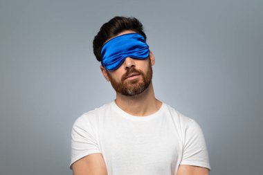 Sweet dreams concept. Asleep middle aged bearded man in sleep mask standing over grey studio background with closed eyes, free space