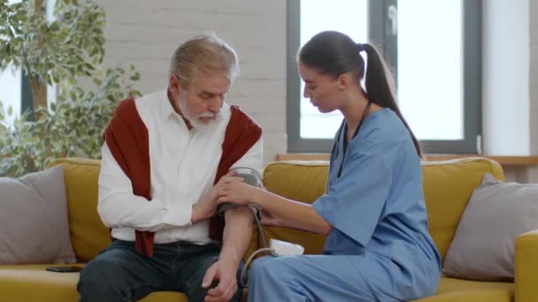 Hypertoni Vid Hög Ålder Ung Kvinnlig Läkare Mäter Arteriellt Blodtryck — Stockvideo