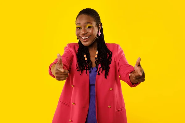 I Choose You. Happy Black Woman Pointing Fingers Looking At Camera Posing Standing Over Yellow Background, Wearing Bright Pink Jacket. Youre Next Concept. Studio Shot