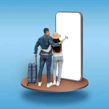 Middle eastern couple with suitcase wear straw hat tourists standing on pedestal over blue studio background, using big phone with white blank screen, booking hotel or flight online, mockup, collage
