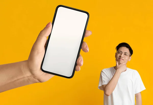 생각깊은 Asian Guy Looking Aside Blank Smartphone Huge Female Hand — 스톡 사진