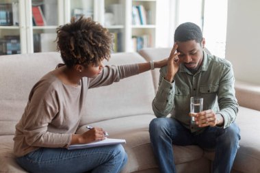 Psychological help, support. Psychotherapist younng african american woman comforting sad frustrated man patient, black lady counselor holding hand on upset guy shoulder, therapist office interior