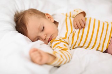 Cute little girl sleeping peacefully on bed, baby having good dream and feeling comfortable, closeup shot. Childcare, bedtime and baby healthy sleep concept