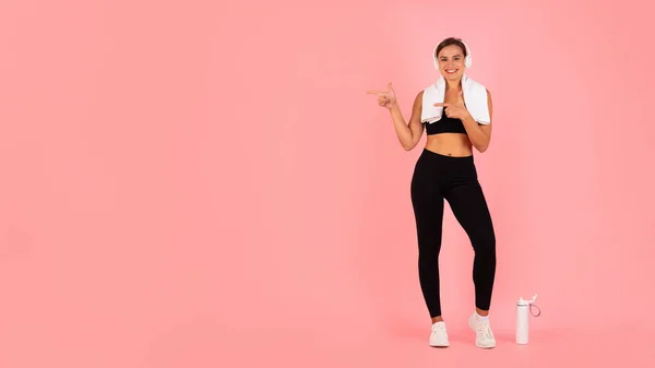 Check This. Sporty Fit Female In Wireless Headphones Pointing Aside At Copy Space With Two Hands, Young Athletic Woman In Activewear Demonstrating Free Place For Advertisement, Panorama